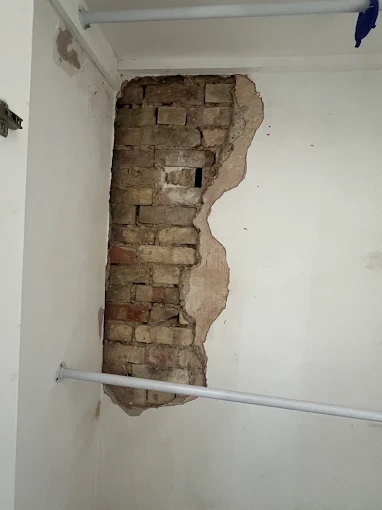 Blown plaster exposed brick, before