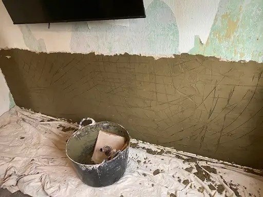 Scratch coat going on a stripped wall, during