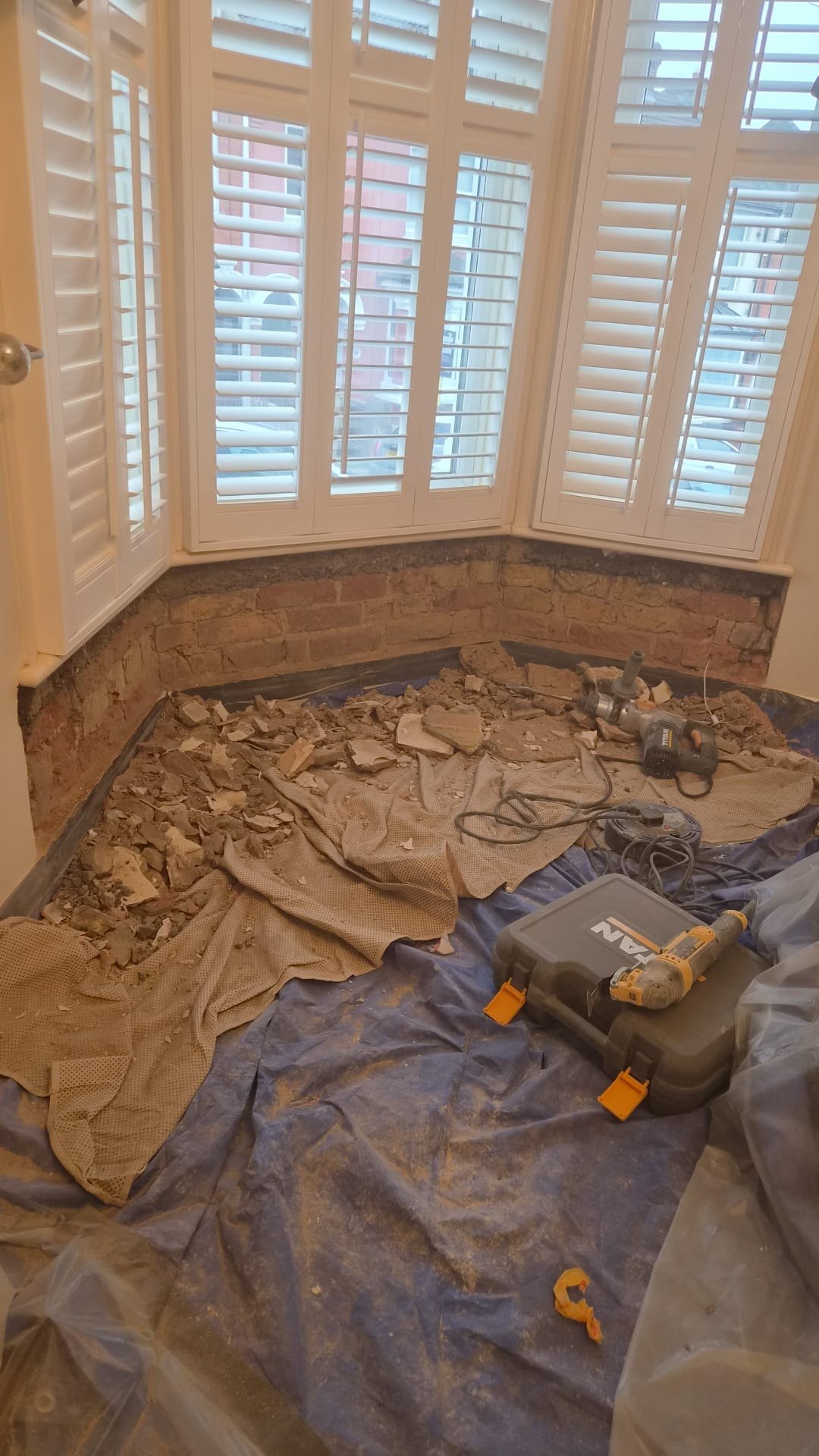 Bay window wall stripped to brick, before