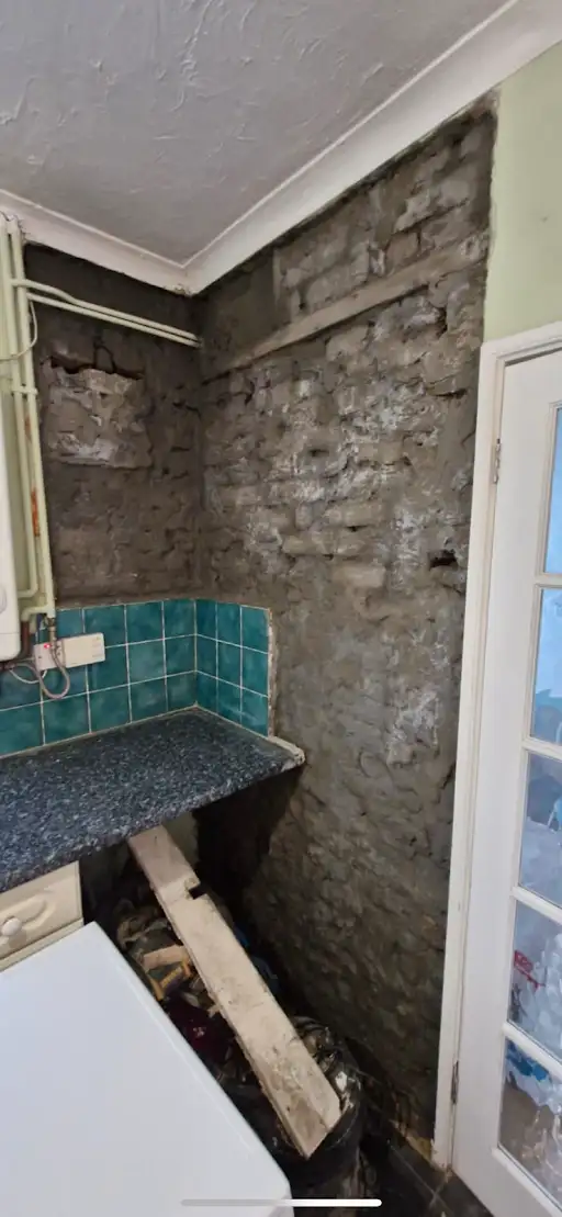 Kitchen wall stripped to brick, before