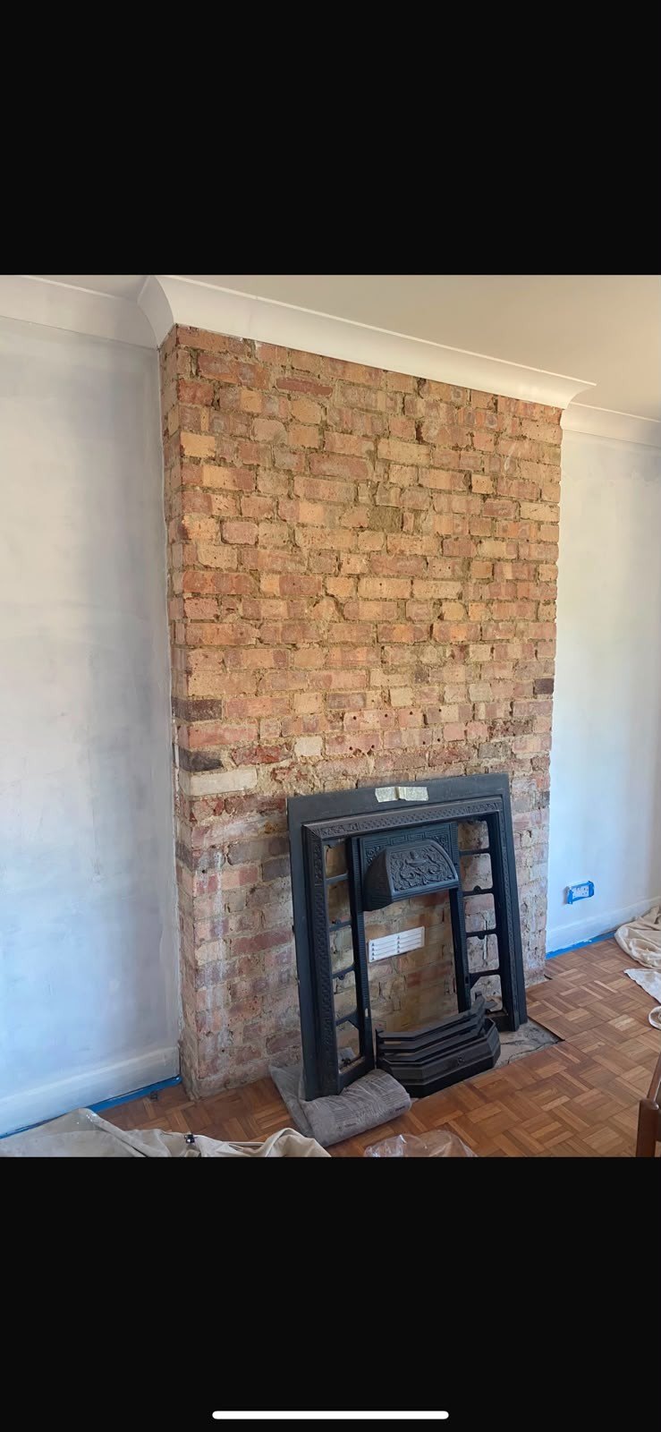 Chimney breast stripped to brick around stove, before