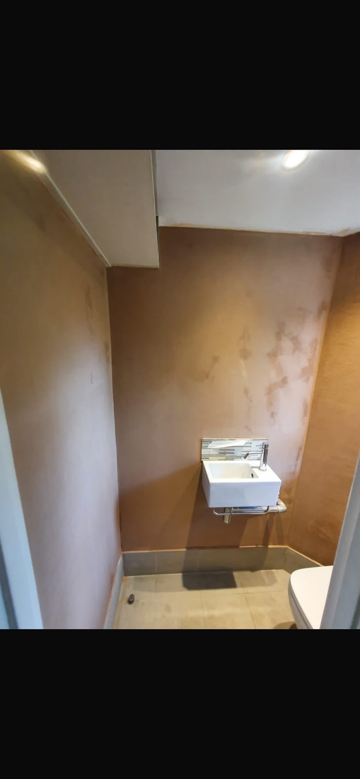 Cloakroom walls skimmed around basin, after