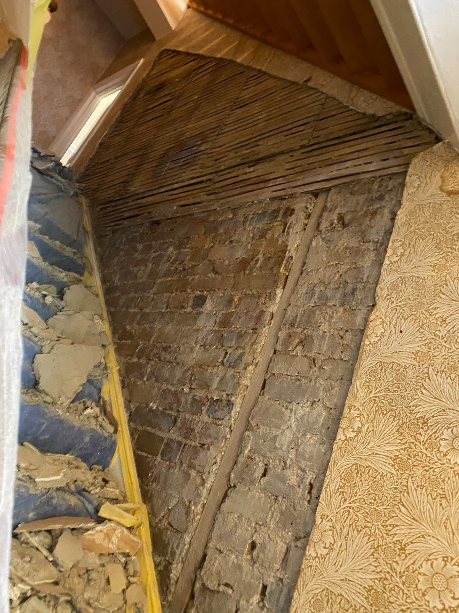 Stairwell wall stripped to brick and lath, before