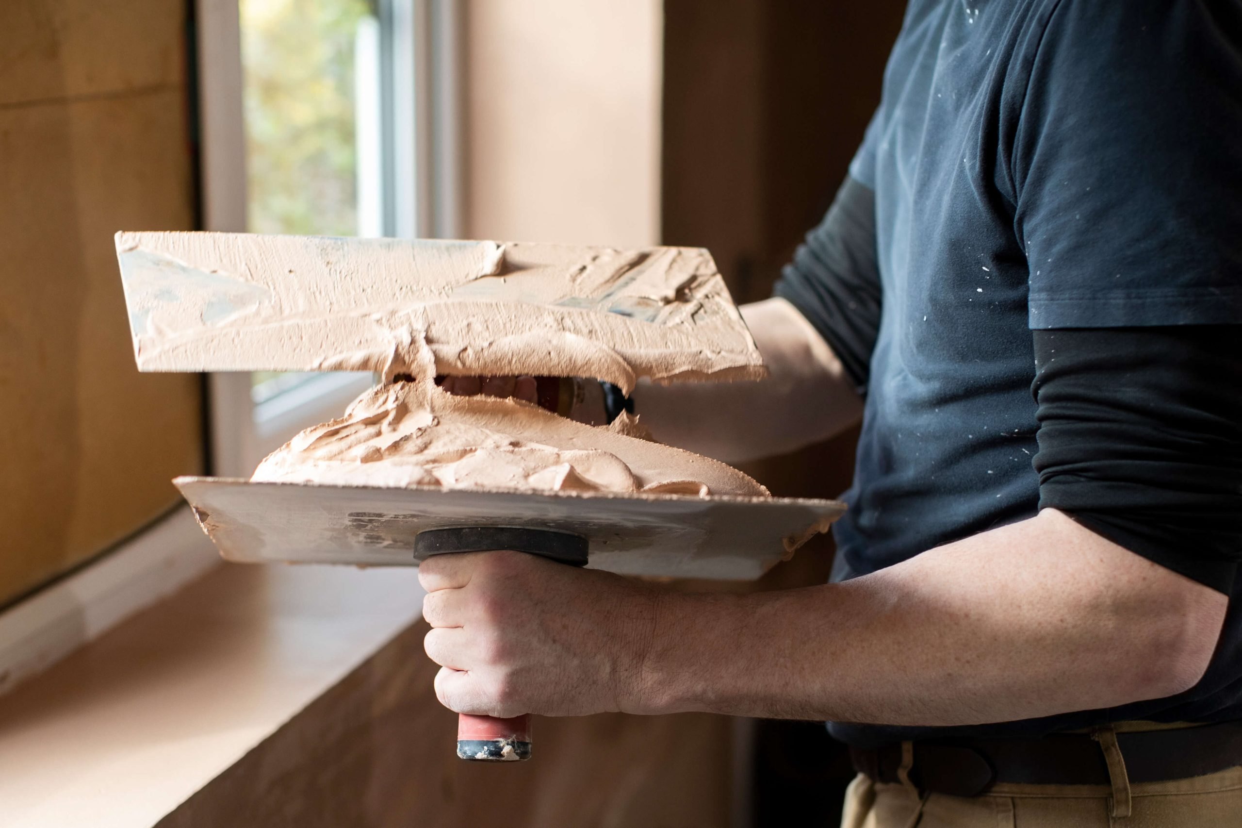 Hawk and trowel loaded with plaster on a job