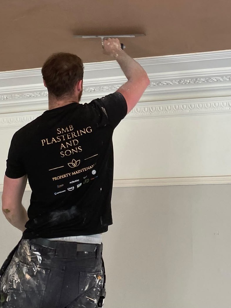 Frank McBride laying on a ceiling skim in an SMB Plastering and Sons shirt